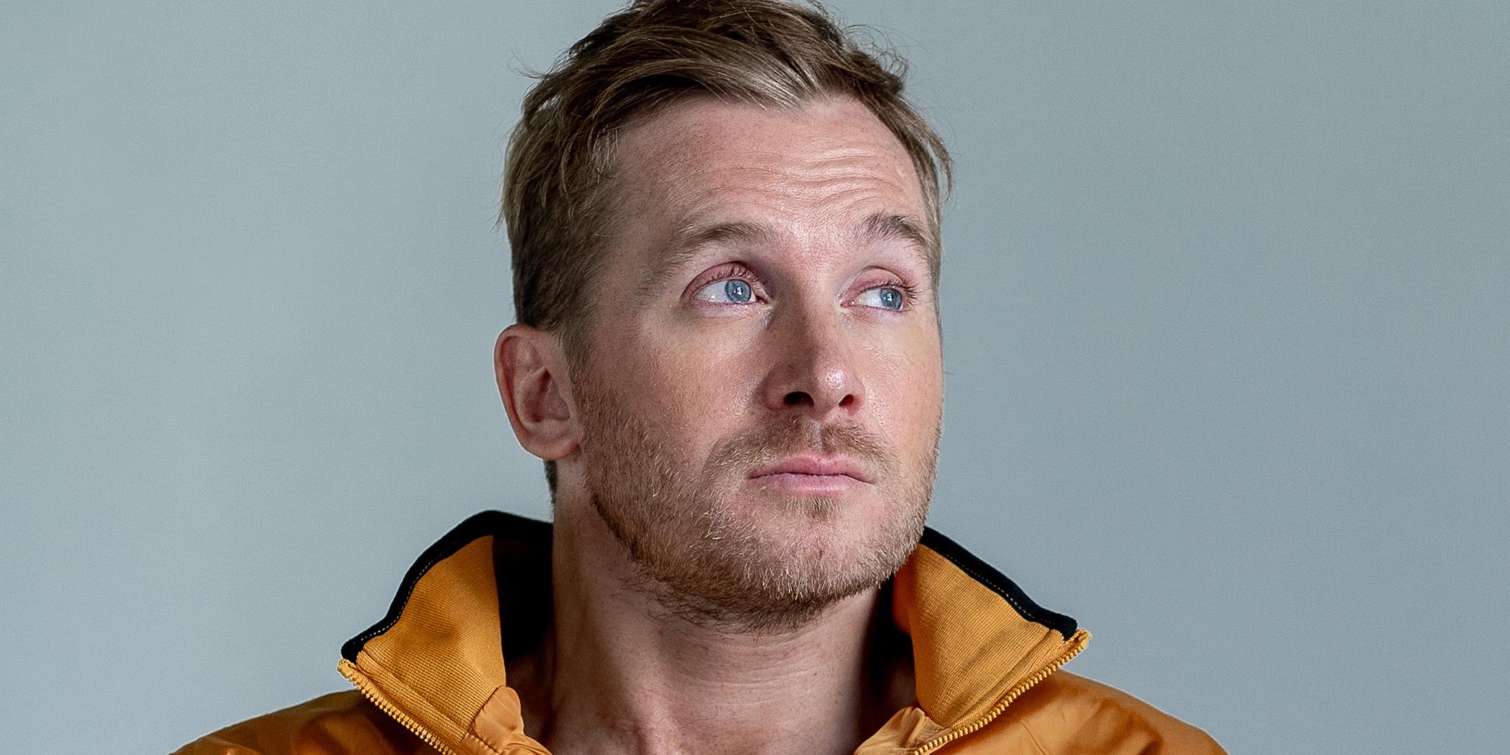 ein Mann vor einem grauen Hintergrund mit einer gelben Jacke