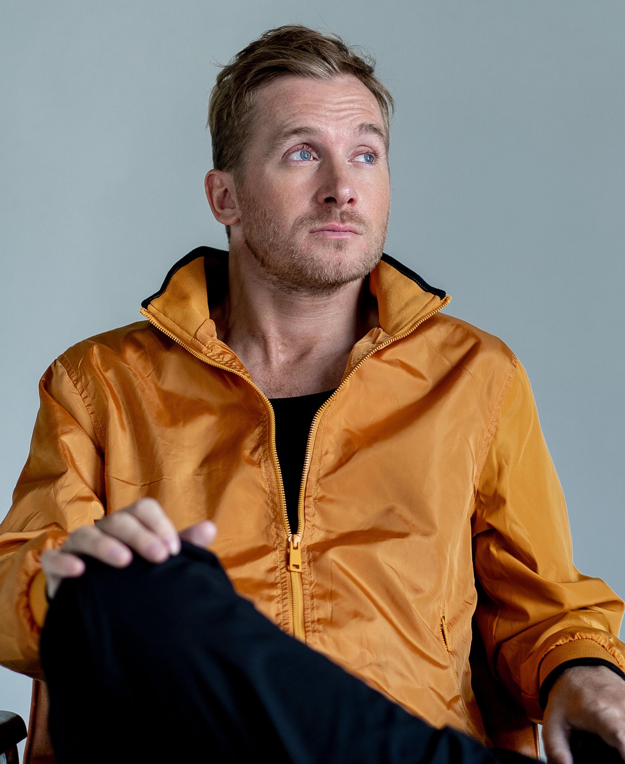 ein Mann vor einem grauen Hintergrund mit einer gelben Jacke