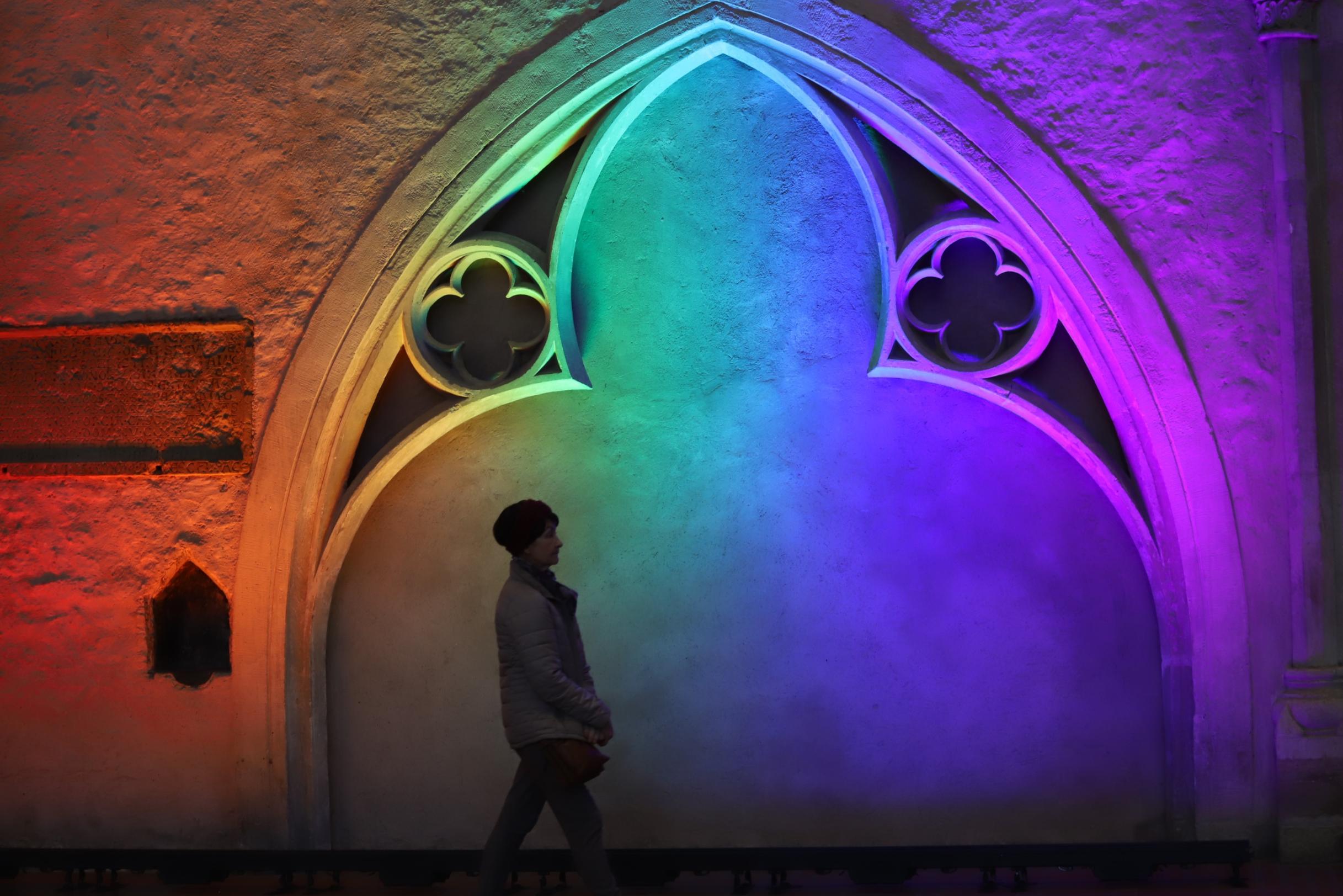 Ein Bild im Dom auf dem man eine Person sieht im Hintergrund bunte Regenbogenfarben