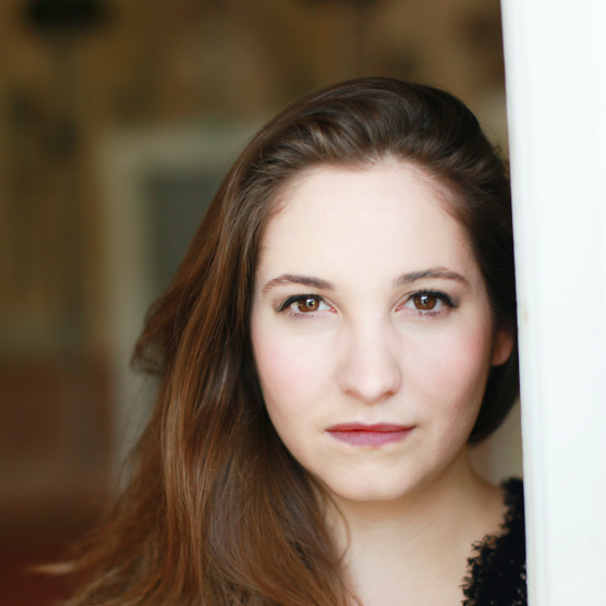 eine Frau mit einem schwarzen Oberteil vor einem verschwommenen Hintergrund