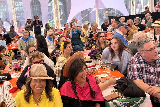 viele bunt gekleidete Menschen sitzen in einem großen Zelt