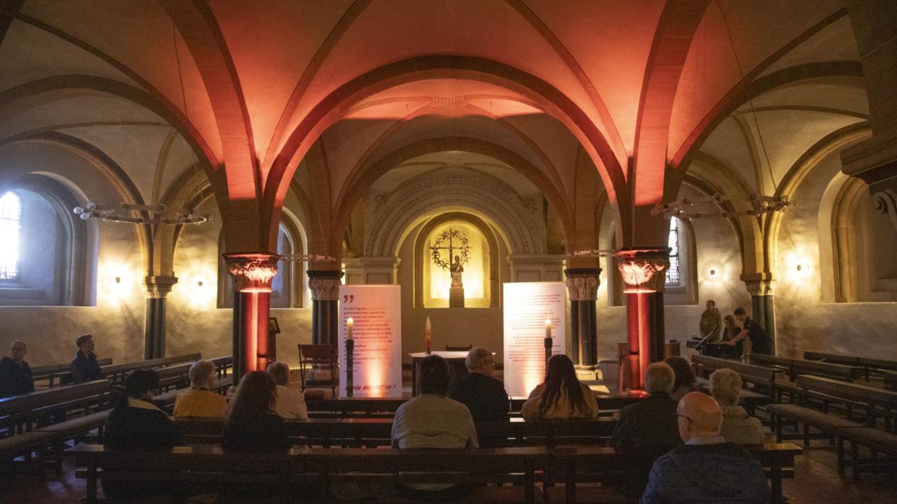 Blick in St. Gangolf - Menschen sitzen vereinzelt auf Kirchenbänken