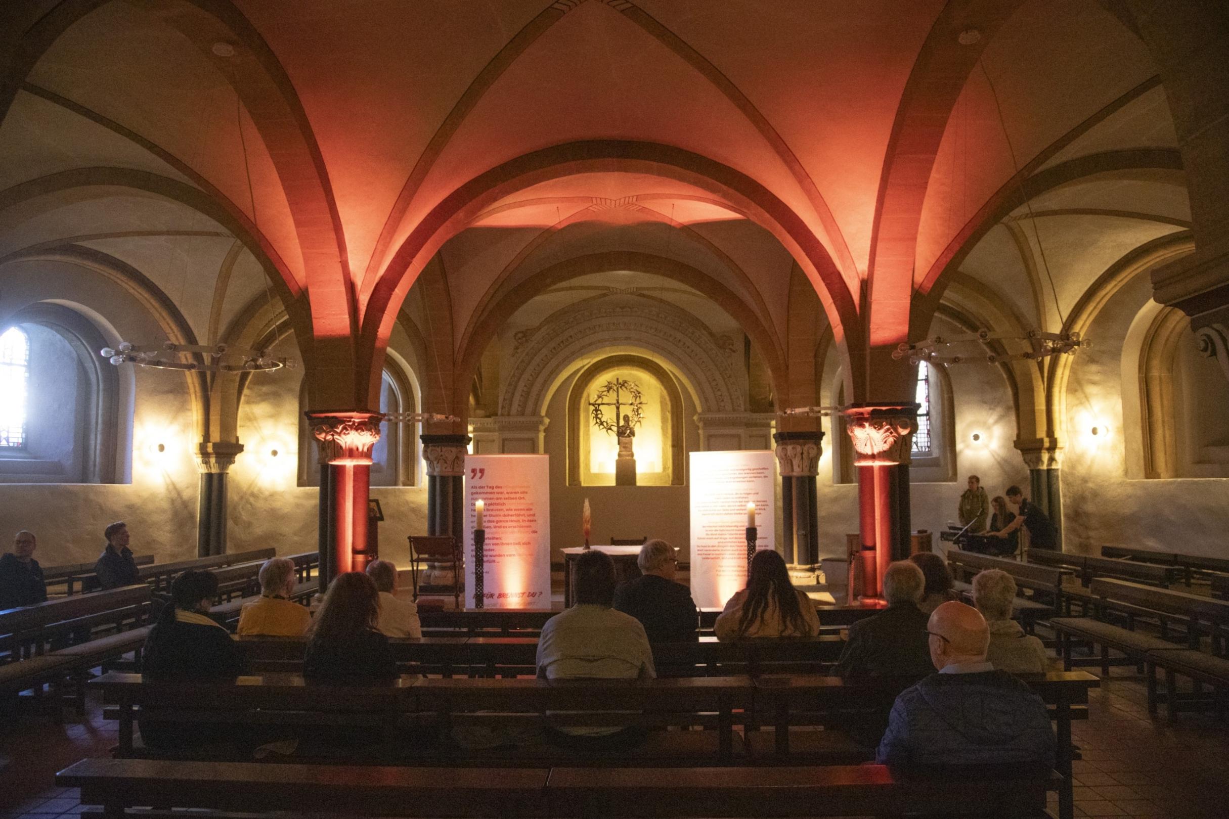 Blick in St. Gangolf - Menschen sitzen vereinzelt auf Kirchenbänken