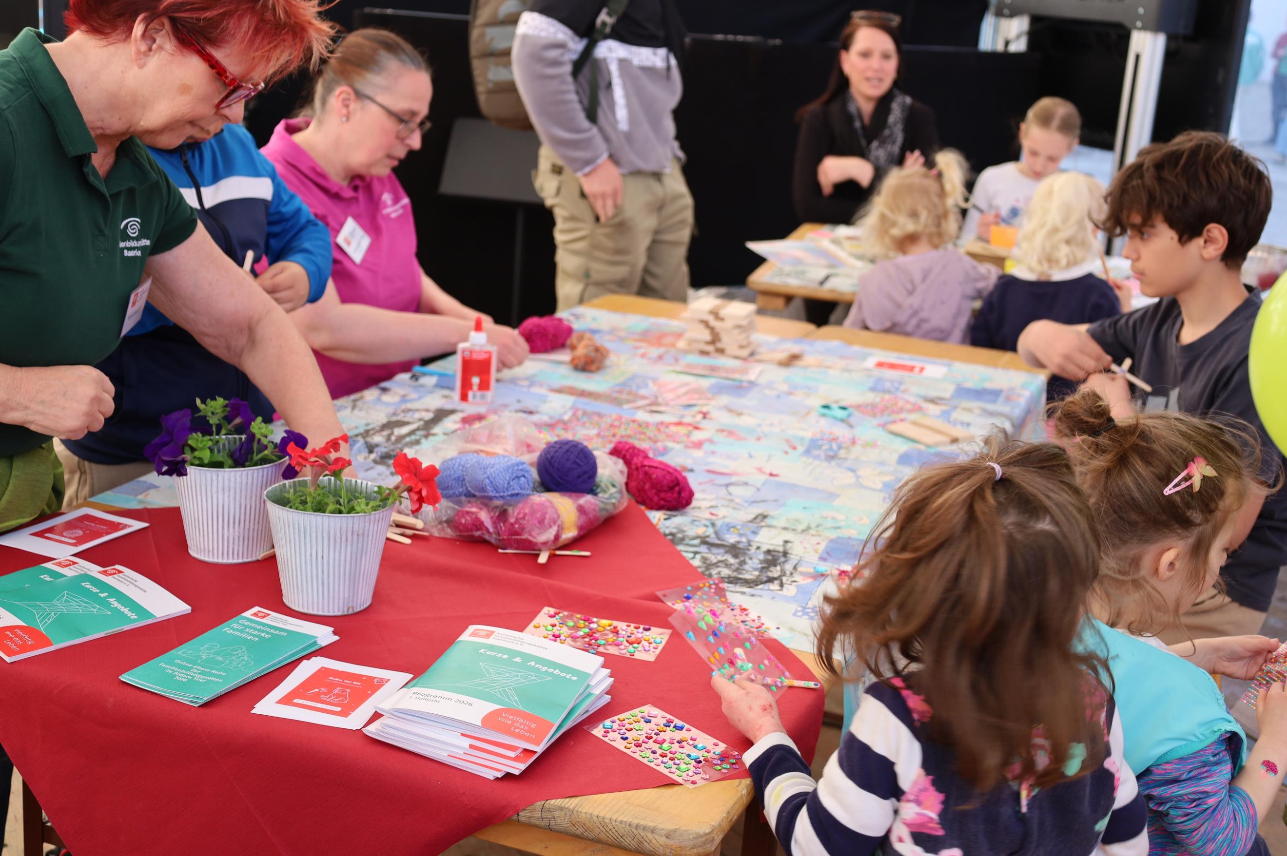 Kinder sitzen an einem Tisch und basteln gemeinsam mit Erwachsenen