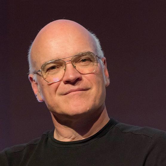 ein Mann mit einem Schwarzen Oberteil vor einem dunklen Hintergrund