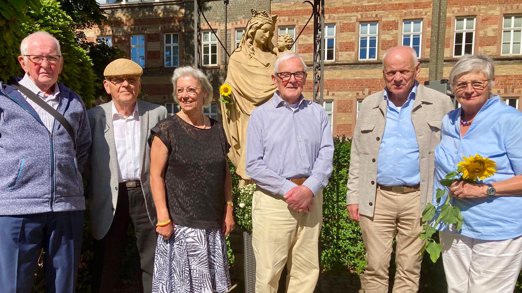 Sechs Personen stehen vor einer Statue für ein Gruppenbild zusammen