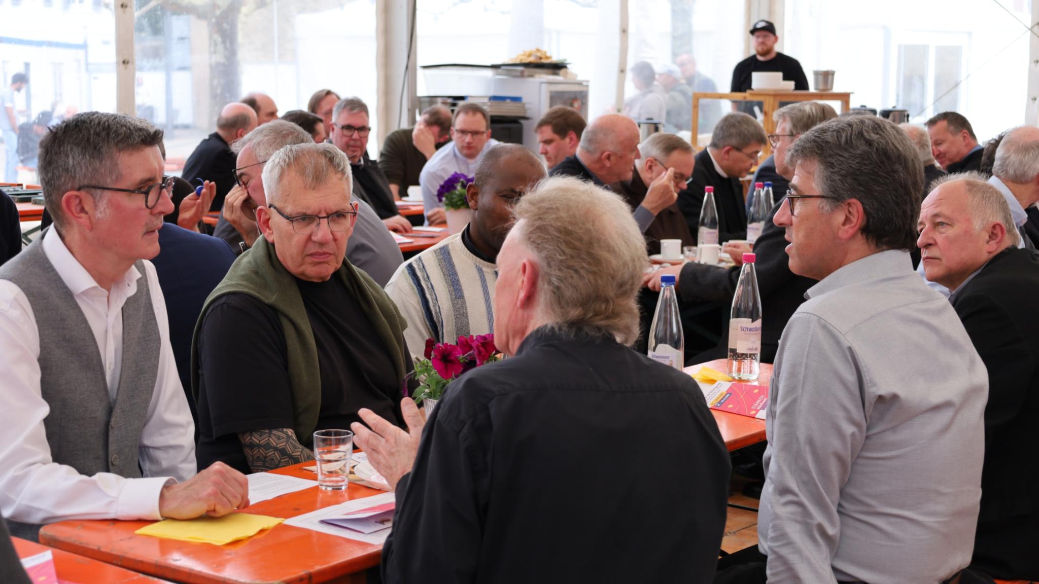 Priester im Austausch im Begegnungszelt