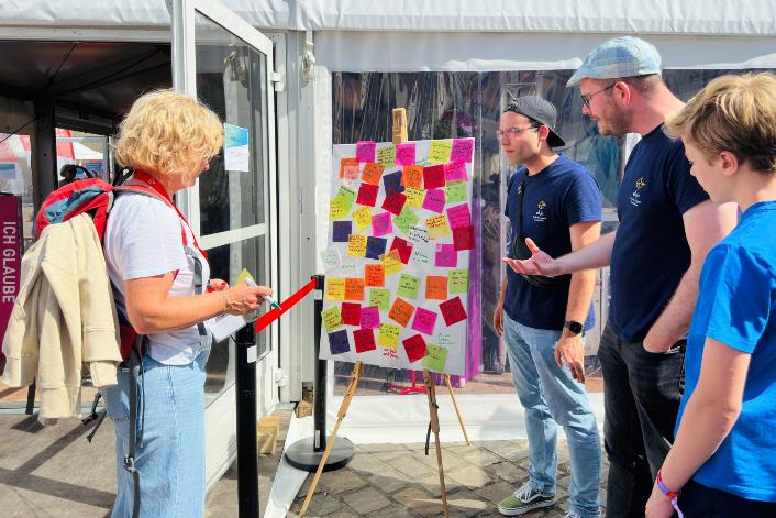 Vier Menschen stehen vor einem Bild mit Klebezetteln