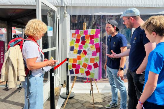 Vier Menschen stehen vor einem Bild mit Klebezetteln