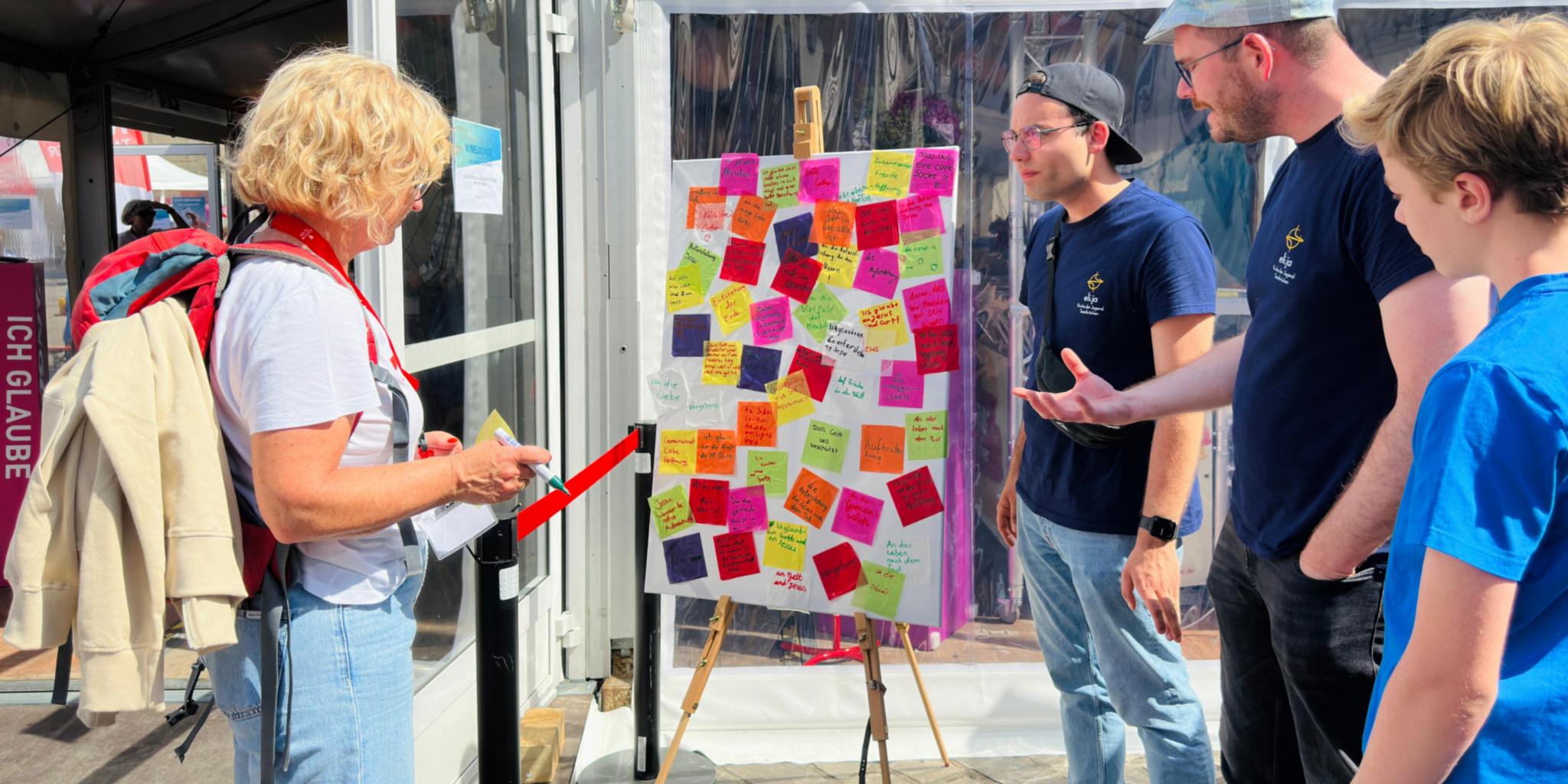 Vier Menschen stehen vor einem Bild mit Klebezetteln