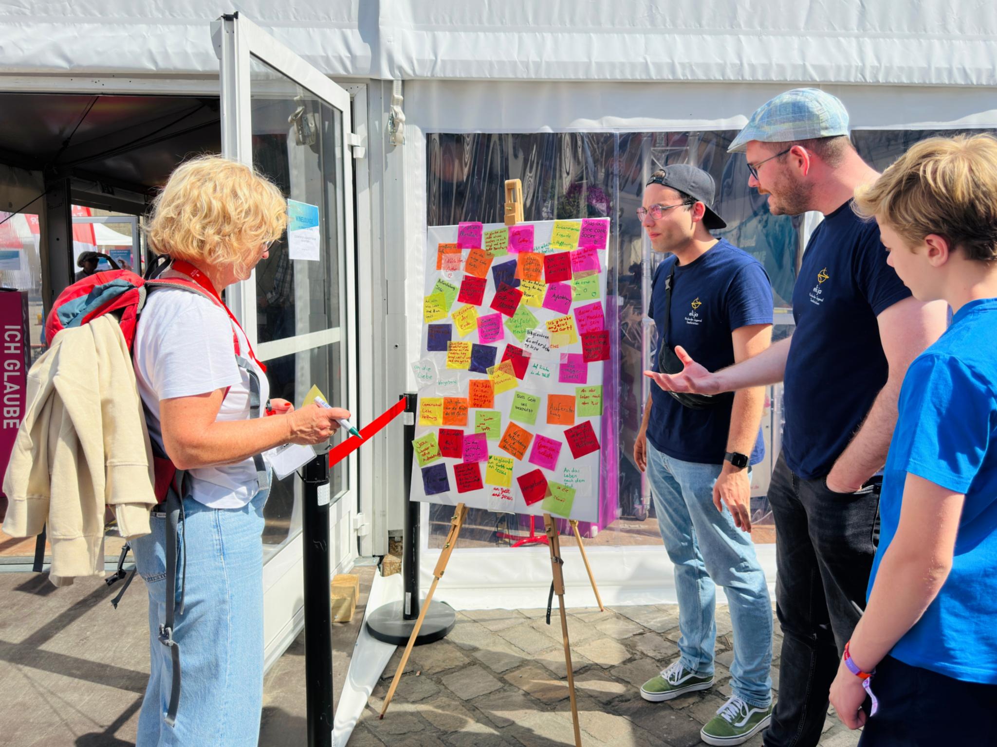 Vier Menschen stehen vor einem Bild mit Klebezetteln