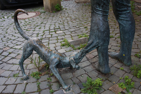 Statuen zeigen einen Hund der sich an einem Hosenbeim fest beisst.