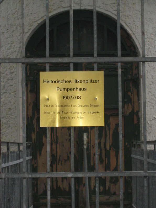 Ein Schild an einem Gittertor vor dem Häusschen mit der Aufschrift "Schacht Pumpenhaus"