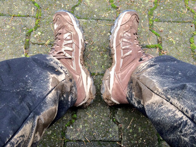 Man sieht mit Matsch überzogene Wanderschuhe und Hose